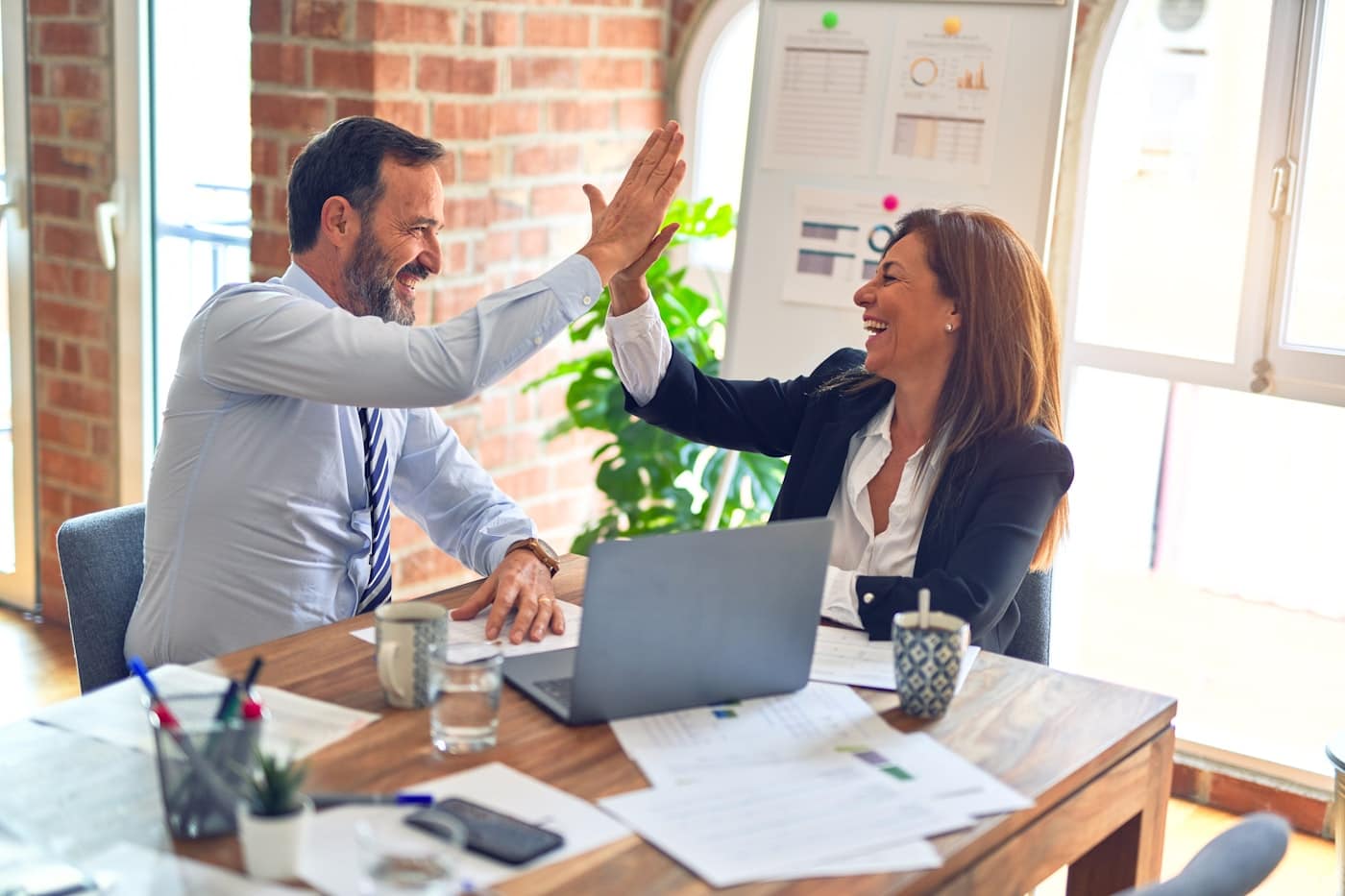 Two middle-age business workers doing hive fives